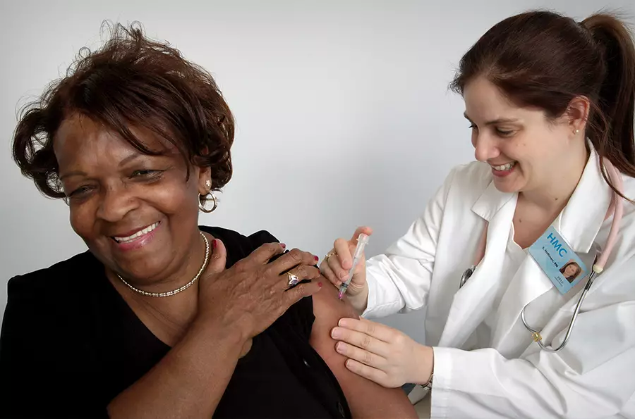 A female doctor administers a shot into a smiling woman's arm